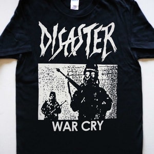 以下が含まれることがあります： バンド「Disaster」と「War Cry」の文字が白でプリントされた黒いTシャツ。グラフィックには、軍服を着た2人の人物が描かれており、1人はガスマスクを着用している。
