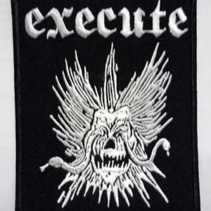 Puede incluir: Parche bordado en blanco y negro con la palabra "execute" en fuente gótica y una calavera blanca con alas y serpientes.