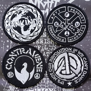 May include: Four black and white embroidered patches with different designs. The patches feature the words "Ankind", "Anti-Product", "Construvene", and "It's Not Our Revolution If We Can't Dance".