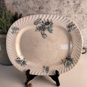 May include: White oval serving platter with a blue and white floral design. The platter has a wavy edge and is decorated with a bouquet of flowers in the centre.