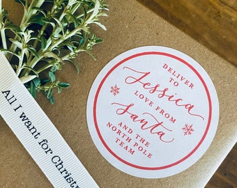 May include: A white gift tag with a red border and snowflakes. The tag says "Deliver to Jessica Love from Santa and the North Pole Team".