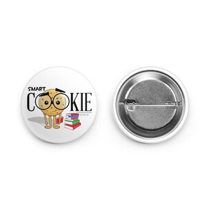 May include: A white button with a cartoon cookie wearing glasses and holding a stack of books. The text "SMART COOKIE" is written above the cookie.