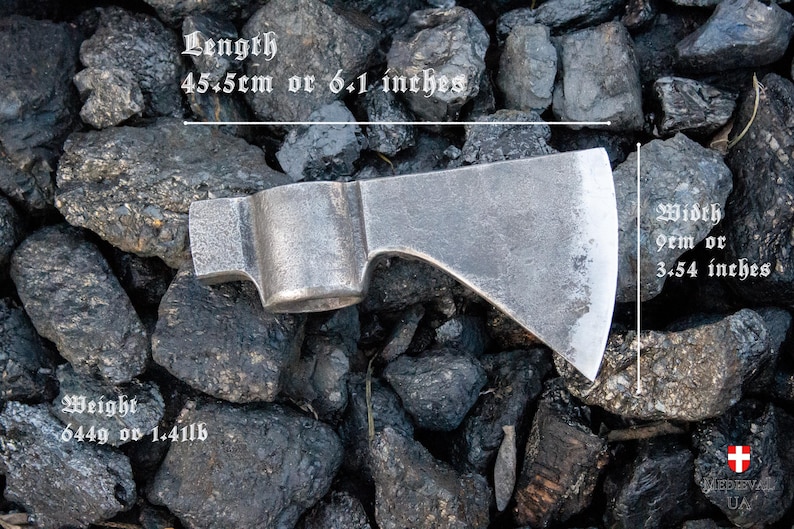 Pode incluir: Um machado de prata com cabo de madeira. O machado tem 15,5 cm de comprimento, 9 cm de largura e pesa 644 g. O machado est&aacute; sobre um leito de pedras pretas.