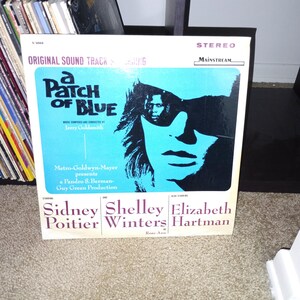 Puede incluir: Portada de álbum de vinilo vintage para "A Patch of Blue". La portada presenta un fondo azul con una silueta negra de un rostro. El título del álbum está en blanco y los nombres de las estrellas se enumeran a continuación.