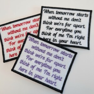 K&ouml;nnte beinhalten: Drei wei&szlig;e Stoff-Patches mit schwarzen R&auml;ndern, jeder mit dem gleichen Text in verschiedenen Farben: "Wenn morgen ohne mich beginnt, denk nicht, dass wir weit entfernt sind. Jedes Mal, wenn du an mich denkst, bin ich direkt hier in deinem Herzen."