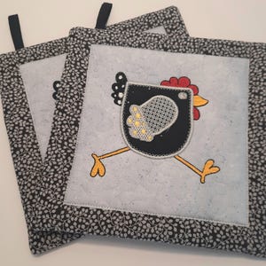 Peut inclure: Ensemble de trois maniques noires et blanches avec un motif de poulet brodé noir et jaune. Les maniques ont un fond blanc avec une bordure à motif floral noir et blanc.