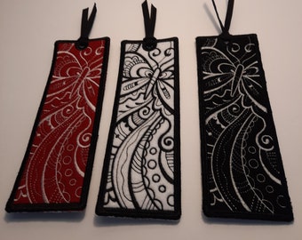 May include: Three fabric bookmarks with a black butterfly design. The bookmarks are red, white, and black.