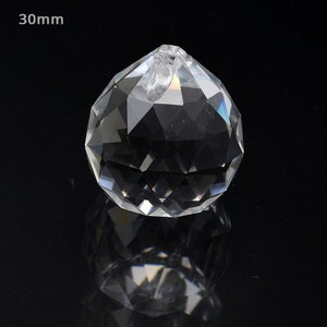 Peut inclure: Une boule de cristal transparente de 30 mm de diam&egrave;tre, avec un design facett&eacute;. La boule a une petite boucle en haut pour la suspendre.