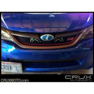 May include: A blue Subaru Impreza with a black and carbon fibre grille. The grille has a red accent strip and a blue Subaru logo. The car has an Ohio licence plate that says "CRUX 1".