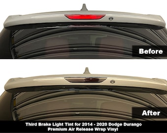 Op de afbeelding: Voor- en nafoto's van een Dodge Durango met een derde remlicht tint. De tint is donkergrijs en bedekt het hele remlicht. De tekst "Third Brake Light Tint for 2014-2020 Dodge Durango Premium Air Release Wrap Vinyl" staat onder de foto's.