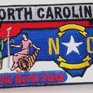 May include: Embroidered patch featuring the words "North Carolina" above a blue outline of the state. The patch includes the state seal, the text "The Old North State," and the year 1789. The patch is bordered in black.
