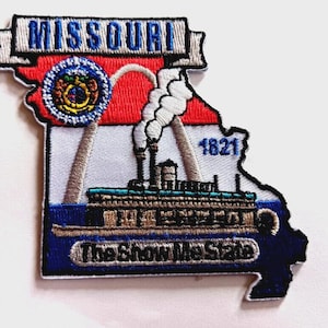 以下が含まれることがあります： ミズーリ州の形をした刺繍パッチ。州名と「The Show Me State」のフレーズが特徴です。デザインには蒸気船、1821年、州の紋章が含まれており、赤、白、青の色が使用されています。