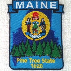 Op de afbeelding: Een blauwe en gele geborduurde patch met het staatszegel van Maine en de woorden "Maine", "Pine Tree State" en "1820".