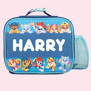 May include: Blue lunch bag with a mesh side pocket. The bag features a Paw Patrol design with the characters peeking over the top. The name "HARRY" is printed in white on the front of the bag.
