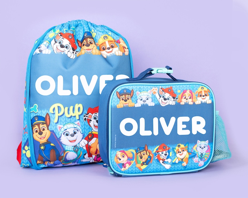 May include: A blue drawstring backpack and a matching rectangular lunch bag featuring Paw Patrol characters. Both items are personalized with the name OLIVER in white text. The designs include various cartoon dogs in colorful outfits.