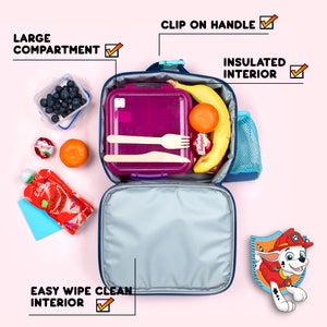 May include: A navy blue lunch bag with a clip on handle and an insulated, easy wipe clean interior. The bag features a large compartment containing a purple food container, a banana, an orange, and a Babybel cheese. Text labels include LARGE COMPARTMENT, CLIP ON HANDLE, INSULATED INTERIOR, and EASY WIPE CLEAN INTERIOR.