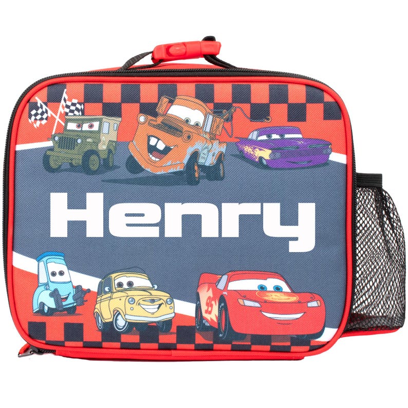 Pode incluir: Uma lancheira retangular com personagens do filme Carros. A bolsa tem um padr&atilde;o xadrez vermelho e preto na parte superior e inferior. O nome "Henry" &eacute; impresso em letras brancas grandes. Um bolso de malha preto est&aacute; na lateral.