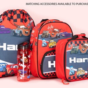 Pode incluir: Um conjunto de acess&oacute;rios vermelhos e azuis com o tema Carros, incluindo uma bolsa com cord&atilde;o, uma mochila, uma garrafa de &aacute;gua e uma lancheira. Os itens apresentam gr&aacute;ficos de carros de desenho animado e o nome "Harry".
