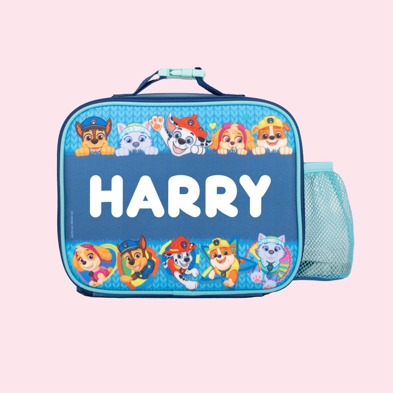May include: Blue lunch bag with a mesh side pocket. The bag features a Paw Patrol design with the characters peeking over the top. The name "HARRY" is printed in white on the front of the bag.