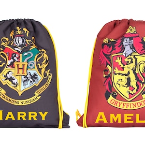 Pode incluir: Duas mochilas de cordão com os brasões das casas de Hogwarts. A mochila à esquerda é preta com o brasão de Hogwarts e o nome "HARRY". A mochila à direita é vermelha com o brasão de Grifinória e o nome "AMELIA".
