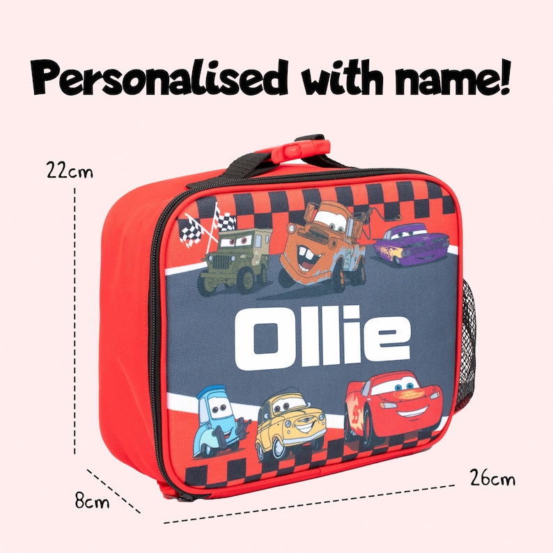 Pode incluir: Saco de almo&ccedil;o vermelho e preto com uma al&ccedil;a, com carros de desenho animado e o nome "Ollie". A bolsa tem 26 cm de comprimento, 22 cm de altura e 8 cm de largura. O texto "Personalizado com nome!" est&aacute; no topo.