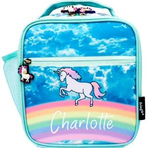 May include: A turquoise blue lunch bag with a unicorn and rainbow design. The bag has a mesh side pocket and a zipper closure. The bag is personalized with the name "Charlotte".