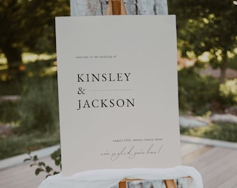 May include: A white sign with black text announcing the wedding of Kinsley & Jackson on August 5th, 2023. The sign is on a wooden easel with a white cloth draped over it.