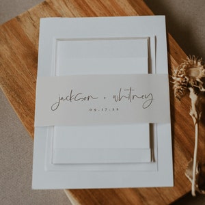 Puede incluir: Conjunto de invitaciones de boda blancas con una banda de vitela que dice "Jackson + Whitney 09.17.22"
