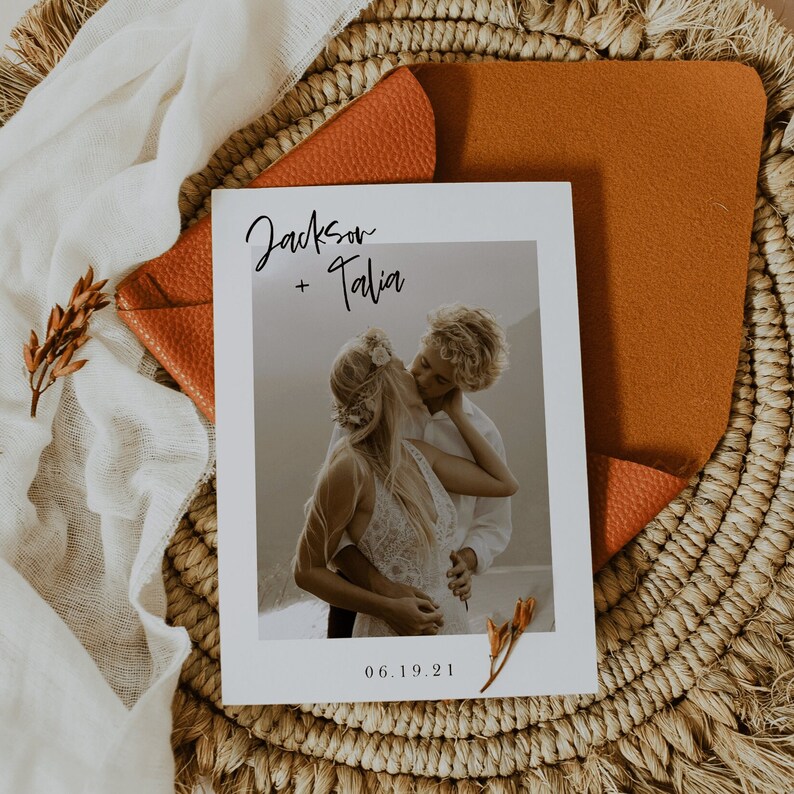 May include: A wedding invitation with a photo of a couple kissing. The invitation is white with black text that says "Jackson + Talia" and "06.19.21".