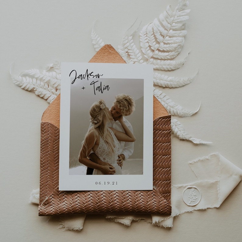 May include: A wedding invitation with a photo of a couple kissing. The invitation is white with black text that says "Jackson + Talia" and "06.19.21".