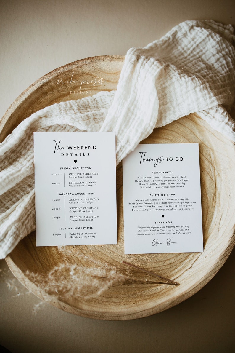 May include: Two white cards with black text outlining the weekend details for a wedding. The first card lists the wedding rehearsal, dinner, ceremony, and reception. The second card lists restaurants and activities to do in the area. The text on the second card includes "Thank You" and the names "Olivia & Ben".
