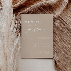 Puede incluir: Una invitaci&oacute;n de boda beige con los nombres "Serena y Jackson" en escritura blanca. La fecha es el 17 de abril de 2021 y el lugar es Canyon Crest Lodge en Denver, Colorado. La invitaci&oacute;n dice "Invite you to celebrate their love and marriage on... Reception to follow."