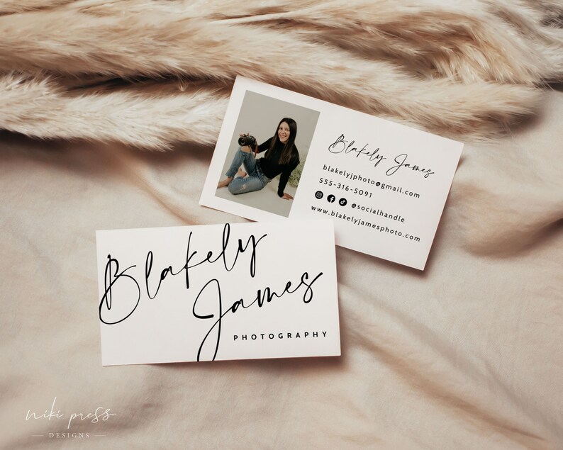 May include: Two business cards with a white background and black text. The top card has a photo of a woman holding a camera. The text on the card reads "Blakely James", "blakelyjphoto@gmail.com", "555-316-5091", "@socialhandle", and "www.blakelyjamesphoto.com". The bottom card has the text "Blakely James Photography".