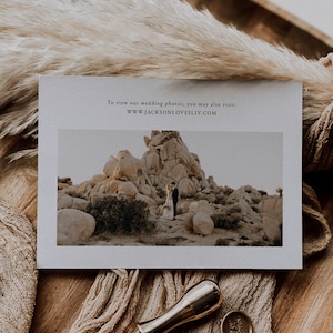 May include: A white card with a photo of a couple standing in front of a rocky landscape. The text on the card reads "To view our wedding photos, you may also visit: WWW.JACKSONLOVESLIV.COM".