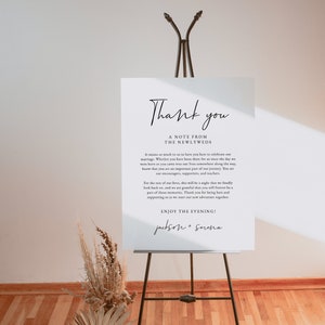 May include: A white sign with black text on an easel. The sign says "Thank you, A Note from the Newlyweds. It means so much to us to have you here to celebrate our marriage. Whether you have been there for us since the day we were born or you came into our lives somewhere along the way, know that you are an important part of our journey. You are our encouragers, supporters, and teachers. For the rest of our lives, this will be a night that we fondly look back on, and we are grateful that you will forever be a part of those memories. Thank you for being here and supporting us as we start our new adventure together. Enjoy the Evening! Jackson + Serena"