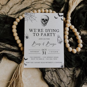 May include: A white Halloween party invitation with black text and illustrations. The text reads "We're Dying to Party" and "Boo's & Booze". The invitation includes the date "October 31st" and the time "7 o'clock".