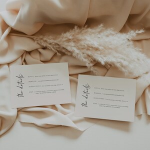 May include: Two white cards with the text "The details" written in black cursive. The cards contain information about an event, including the RSVP, website, directions, and stay. The cards are on a beige fabric background with a dried pampas grass.