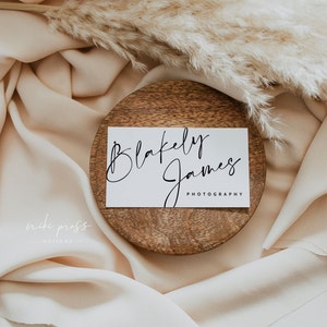 May include: A white business card with the text "Blakely James Photography" in black cursive script, resting on a wooden coaster.