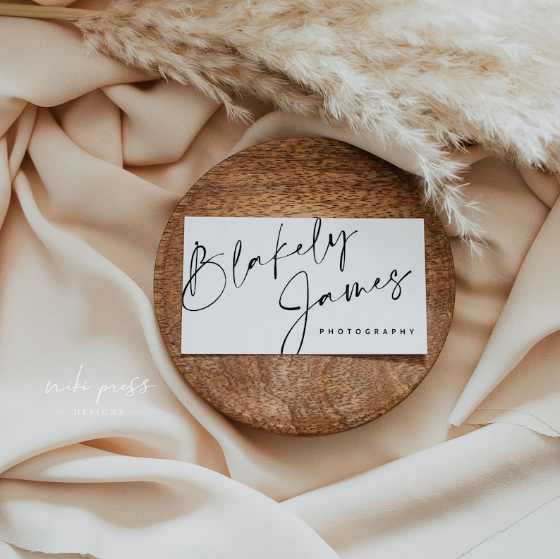 May include: A white business card with the text "Blakely James Photography" in black cursive script, resting on a wooden coaster.