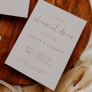 Puede incluir: Una tarjeta de invitaci&oacute;n de color gris claro con texto marr&oacute;n que anuncia una cena de ensayo para Serena y Jackson el 16 de septiembre. La tarjeta incluye detalles sobre los lugares y horarios del ensayo y la cena, as&iacute; como un n&uacute;mero de contacto para las RSVP.