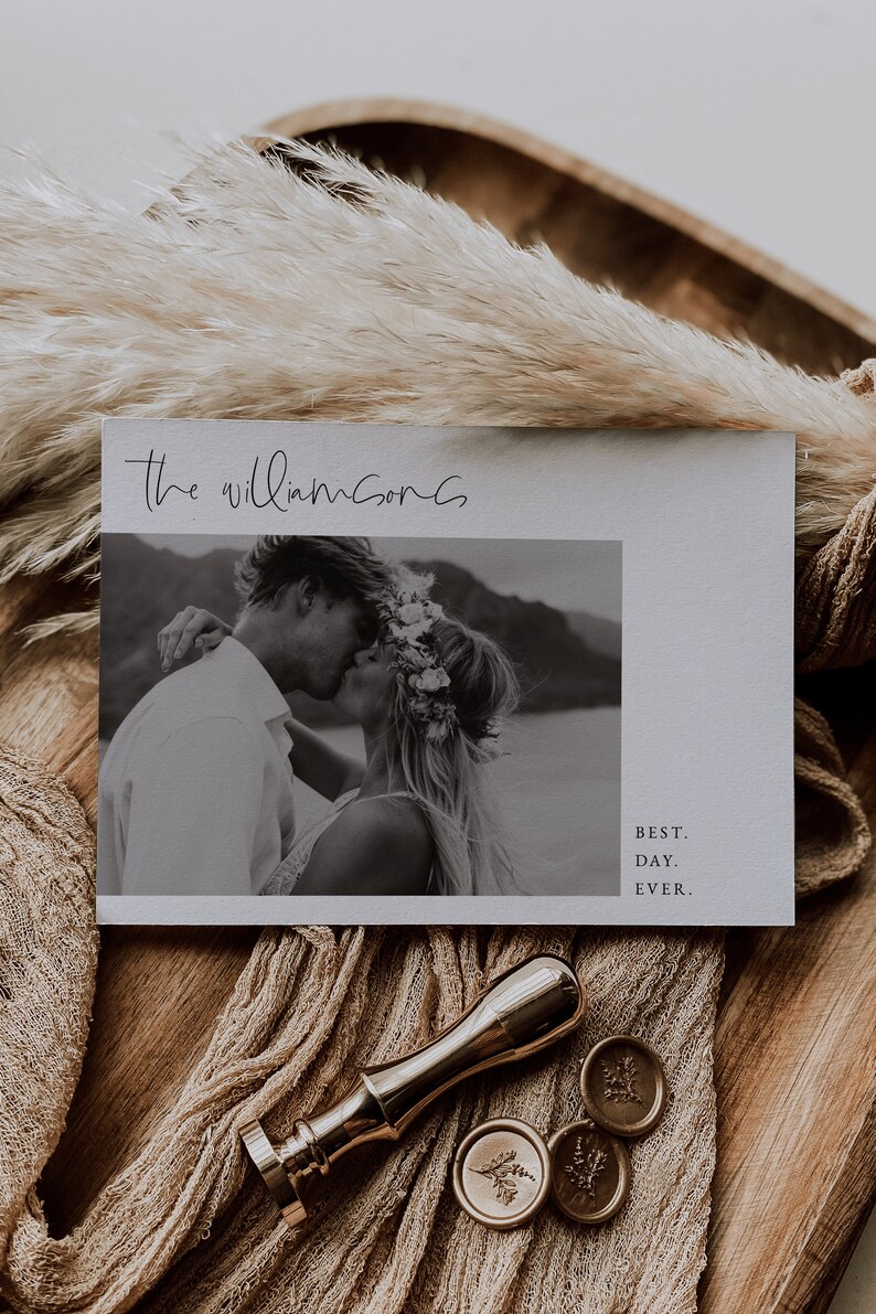 Puede incluir: Una tarjeta de anuncio de boda con una foto en blanco y negro de una pareja bes&aacute;ndose. La tarjeta tiene el texto "The Williamsons" y "Best. Day. Ever." impreso en ella.
