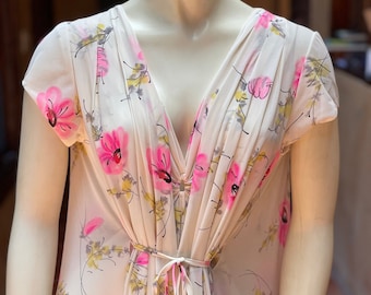 May include: A white floral print nightgown with a V-neckline and short sleeves. The gown has a pink tie at the waist.