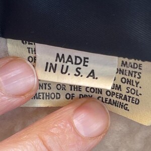 May include: Close-up of a tan fabric label with the text "MADE IN U.S.A." printed in black. The label also includes instructions for cleaning the garment.