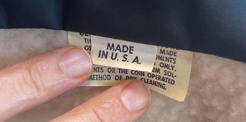 May include: Close-up of a tan fabric label with the text "MADE IN U.S.A." printed in black. The label also includes instructions for cleaning the garment.