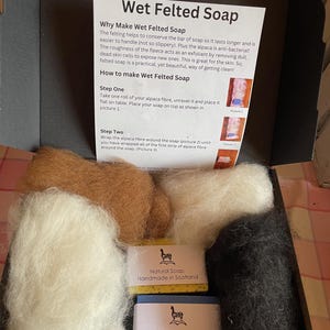 Puede incluir: Una caja que contiene dos barras de jabón natural, hecho a mano en Escocia, y tres paquetes de fibra de alpaca en blanco, marrón y negro. La caja incluye instrucciones sobre cómo hacer jabón de fieltro húmedo usando la fibra de alpaca y el jabón.