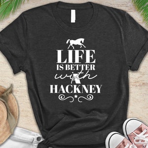 May include: A dark gray t-shirt with a white silhouette of a horse and the text "Life is better with a Hackney".