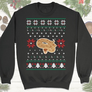 May include: Black Christmas sweater with a red, white, and green snowflake pattern. A brown snake with a white belly is centered on the sweater.