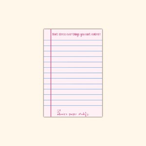 May include: Pink lined notepad with the text "Don't stress over things you can't control!" at the top and the text "*Annie's paper studio*" at the bottom.