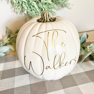 May include: A white pumpkin with a gold inscription that reads "The Walkers".