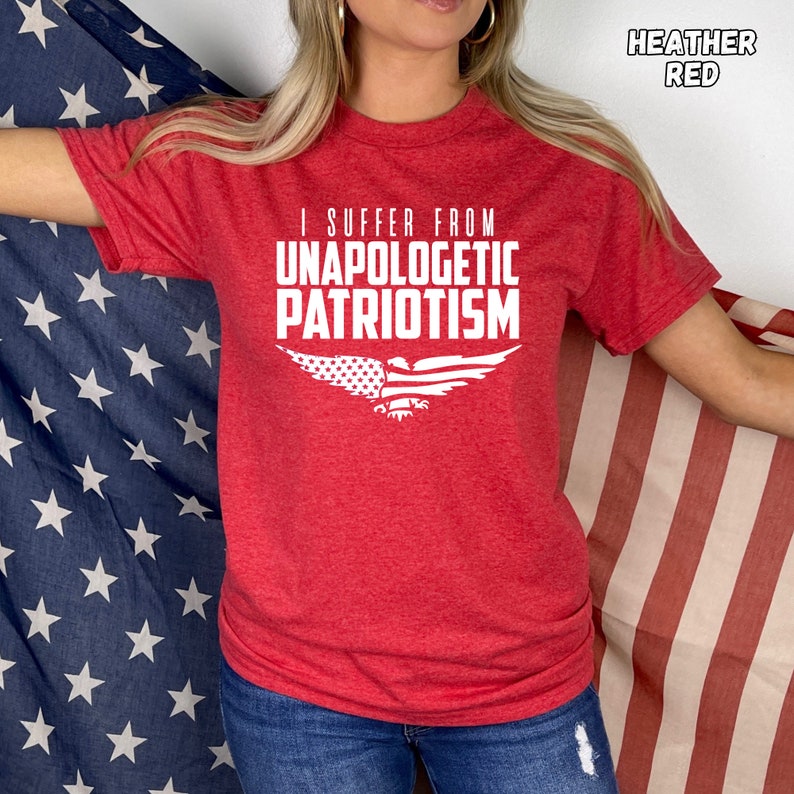 Op de afbeelding: Een rood heather t-shirt met de tekst "I suffer from Unapologetic Patriotism" en een witte adelaar met een Amerikaans vlagontwerp op zijn vleugels.